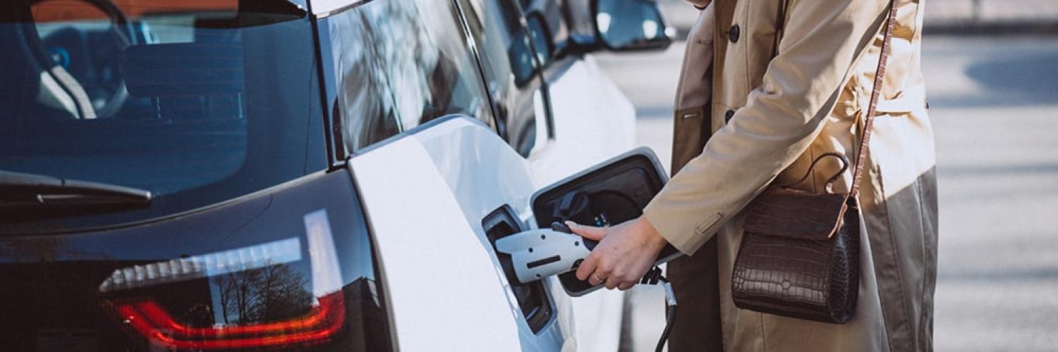 Woman charging electric vehicle