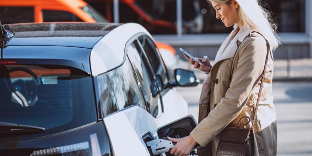 Woman charging electric vehicle